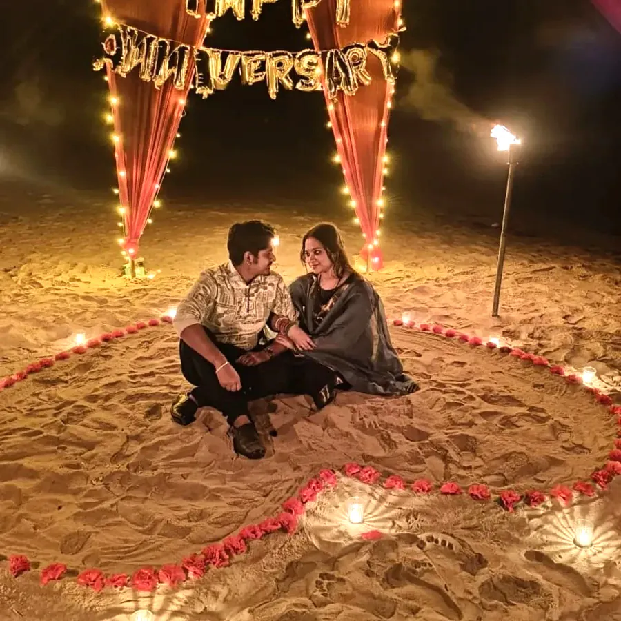 Couple sitting inside a heart of flowers on the sand