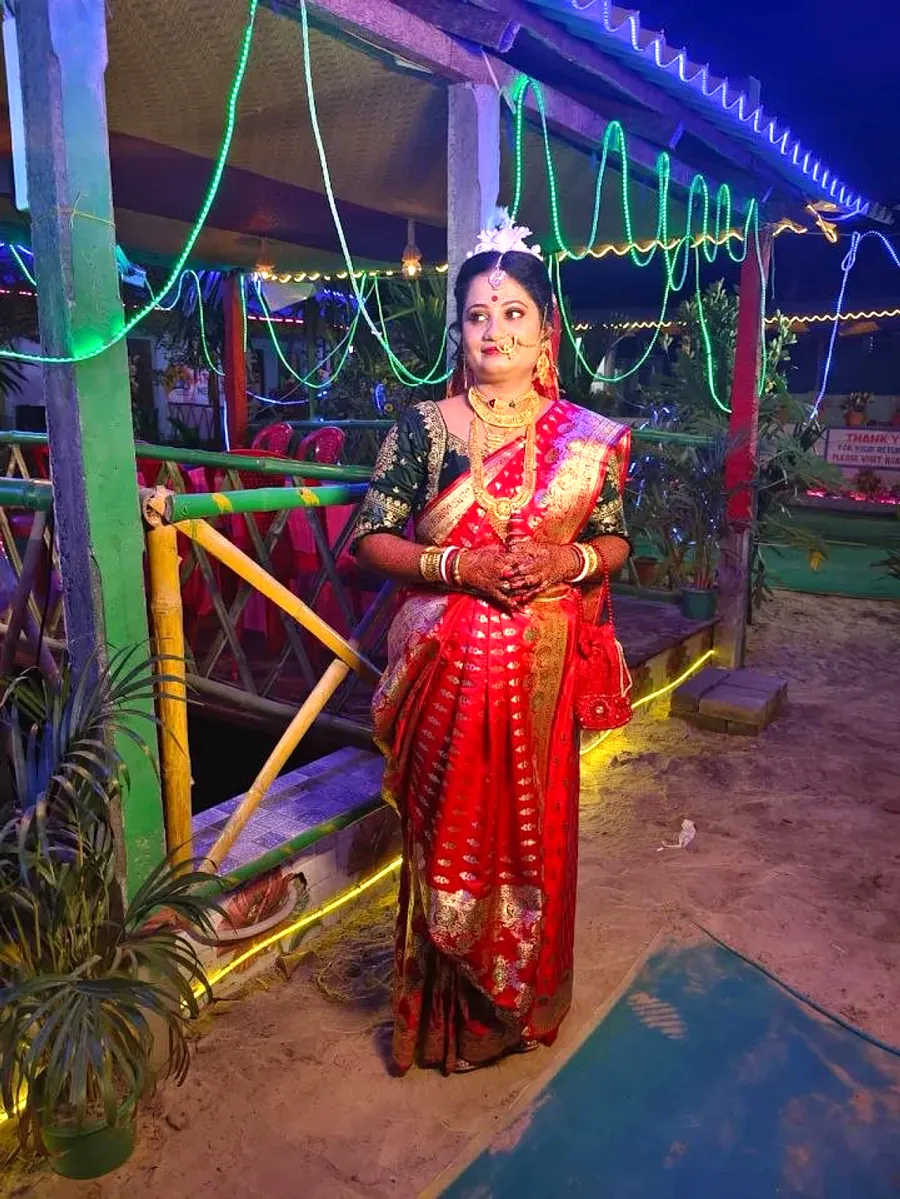 Bride in red saree posing at the lit dining deck