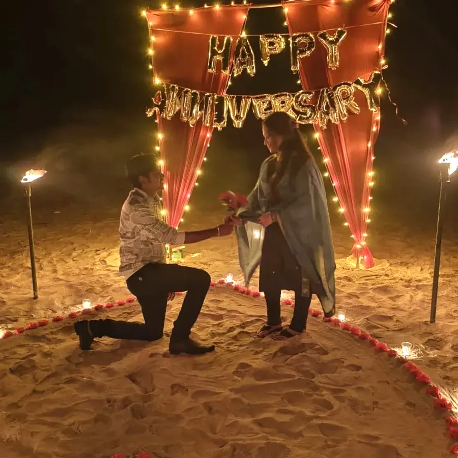Proposal on one knee under anniversary lights